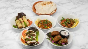 Middle Eastern hot mezze platter with falafel, stuffed vine leaves, meat wraps, spiced vegetables and fresh Arabic bread.