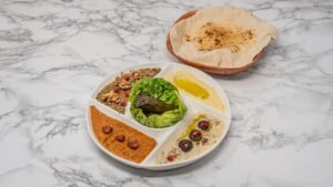 Middle Eastern cold mezze platter with hummus, muhammara, baba ganoush, stuffed vine leaves and fresh Arabic bread.