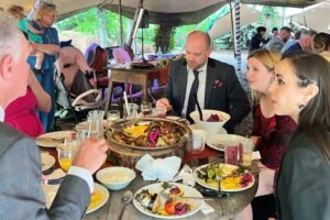 Guests enjoying a shared Middle Eastern meal at an outdoor dining event, with grilled meats, rice, salads and colourful dishes on the table.