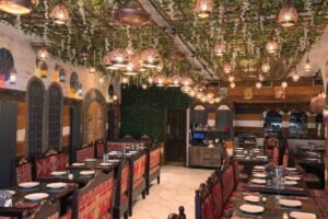 Elegant Damastique restaurant interior featuring traditional Middle Eastern décor, patterned seating, greenery, and ornate hanging lanterns.