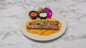 Grilled minced lamb kebabs served on yellow rice with fresh herbs, pickled onions and dipping sauces.