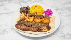Mixed grill platter with grilled chicken, lamb kebab, kofta, yellow rice, salad, pickled turnips and Arabic bread.